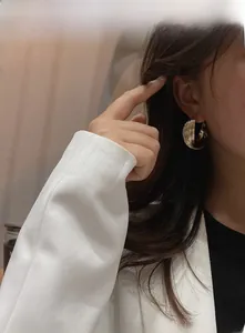 Close-up of golden multi-layer textured hoop earrings worn by a model for a chic look