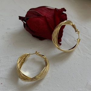 Detailed macro view of layered golden multi-wrap hoop earrings with a metallic finish