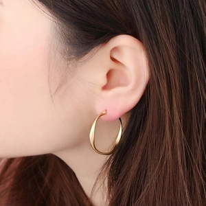 Classic golden twisted C-shaped hoop earrings worn by a model in a minimalist style