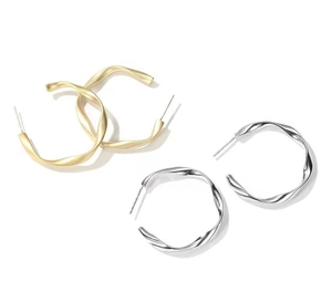 Detailed close-up of C-shaped twisted metal hoop earrings in matte gold and silver finish