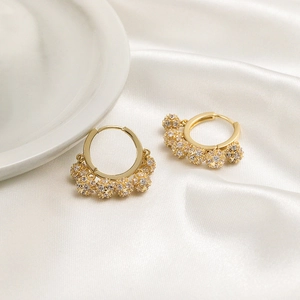 Elegant gold hoop earrings with sparkling crystal-encrusted spheres on white silk