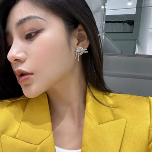 Irregular knotted brass earrings in silver finish on model wearing yellow blazer