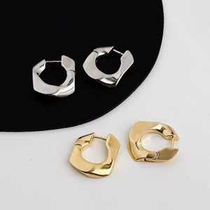 Close-up of geometric irregular metal hoop earrings in shiny gold and silver finishes