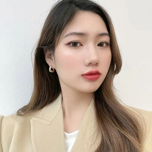 Close-up of elegant gold square hoop earrings worn by a model in a minimalist setting