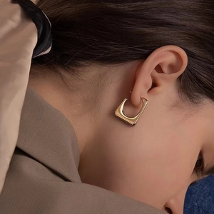 Minimalist geometric gold square hoop earrings worn by a model in a luxury style