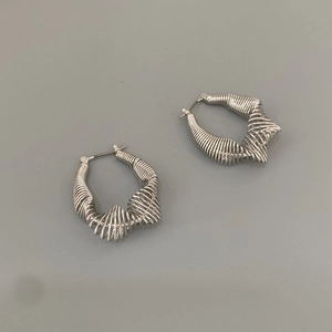 Close-up of geometric silver metal coil earrings with unique industrial wire wrap design