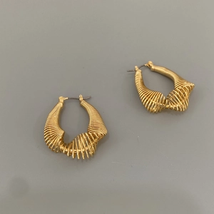 Detailed view of gold spiral metal hoop earrings with a textured teardrop design