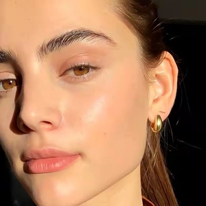 Minimalist thick golden hoop earrings with solid metallic texture worn by a model