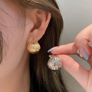 Textured metallic dome stud earrings in gold and silver finish shown on a model