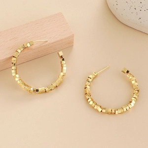 Boucles d'oreilles créoles C dorées élégantes avec perles polies sur fond minimaliste chic