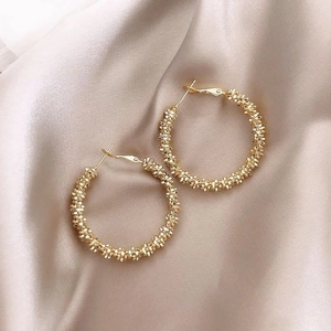 Strukturierte 18K vergoldete Creolen mit geometrischem Korn-Design auf Seidenhintergrund