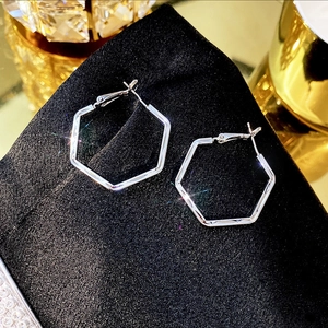 Macro shot of silver hexagon hoop earrings with polished finish on black silk