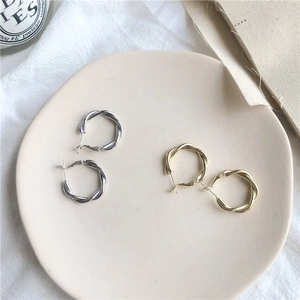 Classic twisted metal hoop earrings in gold and silver finish for a minimalist chic style