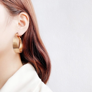 Golden multi-layered hoop earrings with brushed metal finish on model's profile