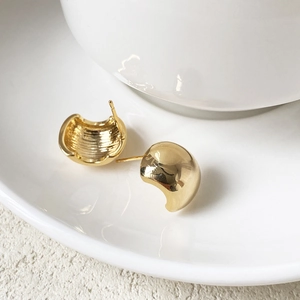Detailed view of gold metal earrings showing brushed texture and polished finish details