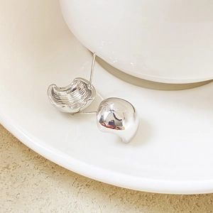 Macro shot of minimalist silver metal stud earrings with polished mirror-like surface