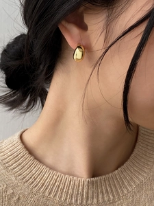 Close-up of elegant polished golden crescent moon earrings on model in warm lighting