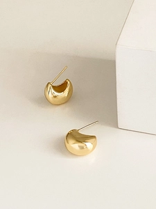 Close-up of polished golden C-shaped hoop earrings on a minimalist white background