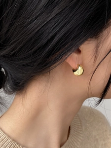 Macro view of polished gold crescent moon earrings showing glossy metallic texture