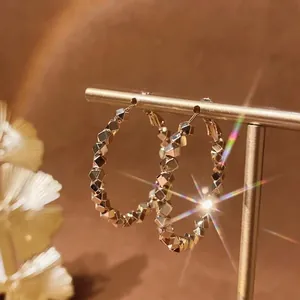 Elegant geometric gold hoop earrings with multi-faceted metallic mosaic design