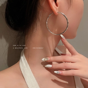 Minimalist large silver geometric hoop earrings worn by a model in a high-fashion style