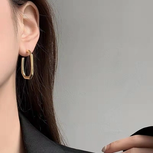 Polished gold geometric rectangular stud earrings worn by a model for a minimalist look