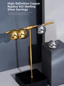 Detail of high-polish brass ball earrings with 925 sterling silver needles on a stand