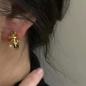Minimalist geometric gold metal spiral hoop earrings shown on a female model