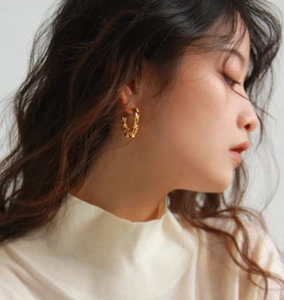 Close-up of golden bamboo hoop earrings on model featuring elegant metallic texture