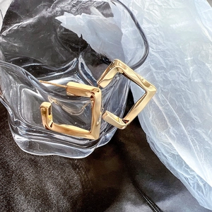 Minimalist geometric 14K brass earrings with a golden twisted frame design on glass