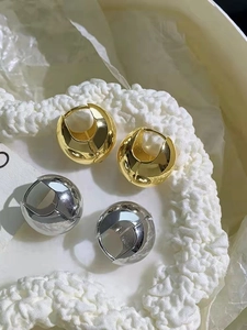 Close-up of gold and silver chunky teardrop hoop earrings with high-polish metallic finish