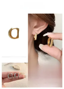 Close-up of D-shaped gold and silver earrings with fine metal engraved details