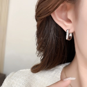 Macro shot of silver U-shaped earrings with delicate engraved logo on polished metal