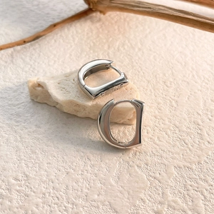 Macro detail of wide silver metal hoop earring with mirror finish on textured stone