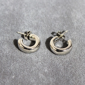 Polished silver chunky C-shaped hoop earrings on minimalist stone textured background