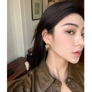 Boucles d'oreilles créoles dorées en forme de C avec design triple sur un mannequin