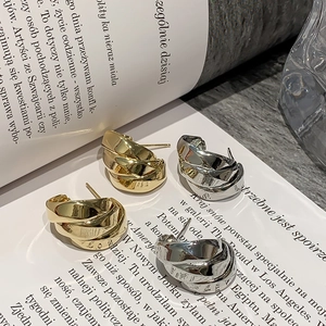 Macro detail of chunky gold and silver twisted hoop earrings on a fashion magazine