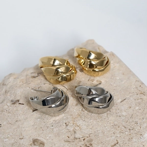 Detailed shot of multilayer twisted hoop earrings in gold and silver finish