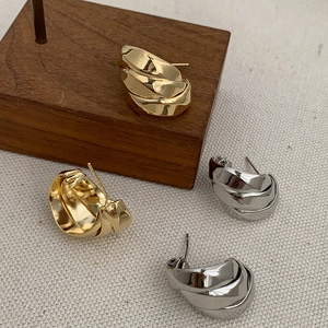 Detail of multi-layered 14K gold and silver chunky C-shaped hoop earrings