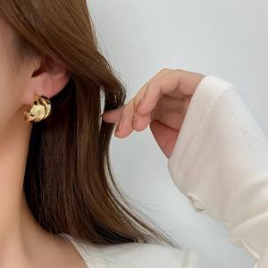 Polished 14K gold-plated chunky twisted hoop earrings shown on a model with white shirt