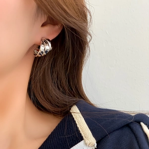 Close-up of model wearing twisted silver C-shaped hoop earrings with a polished metal finish