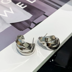 Detailed view of layered silver-toned twisted ribbon earrings with a polished mirror finish