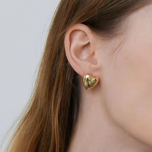 Elegant gold-tone 3D heart stud earrings featuring a high-polish mirror finish on model