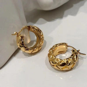 Detailed view of golden quilted metal hoop earrings featuring luxury textured finish