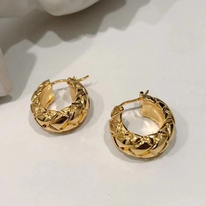 Detailed view of golden hoop earrings featuring a diamond lattice texture and polished finish