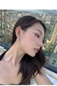 Close-up of sparkling zircon butterfly stud earring worn by a model against a city skyline