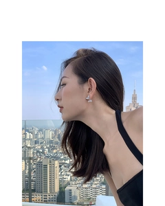 Detail of silver butterfly earrings with zircons worn by model against a city skyline
