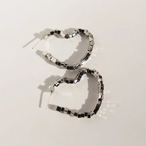 Square beaded heart-shaped earrings with metallic silver geometric texture and bold shadows