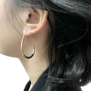 Polished 14K gold plated brass teardrop hoop earrings on model with high gloss finish