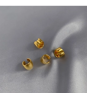 Detailed view of four-piece gold ear cuff set on elegant grey silk background texture